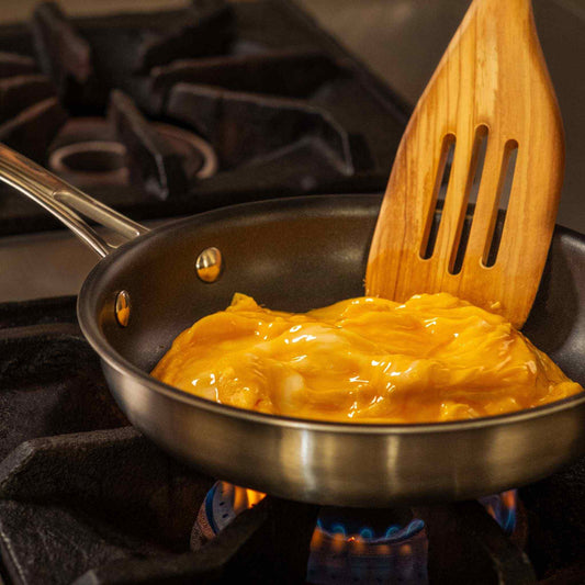 frying a scrambled egg with an olivewood slotted turner on a 8" non stick frying pan